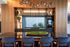 Elegant modern kitchen with sleek black countertop, stylish shelving, and a large window overlooking greenery. Cozy dining space with plush blue chairs offers a harmonious blend of luxury and comfort.