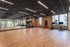 Spacious and modern fitness studio with bright natural light, featuring mirrored walls, exercise bikes, and ample space for workout routines.