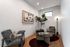 Cozy modern living space with stylish armchairs, abstract art, and elegant lighting beside a vibrant indoor plant.