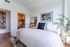 Bright and inviting bedroom with modern decor, featuring a cozy bed, chic artwork, and an ensuite bathroom for convenience.