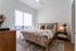 Bright and inviting bedroom with a comfortable bed, stylish pillows, and modern wooden furniture, exuding a cozy and sophisticated atmosphere.