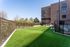 Inviting apartment community featuring a lush green courtyard with modern fencing, perfect for relaxation and outdoor activities.