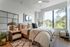 Elegant bedroom with large window views showcasing nature, stylish decor, and cozy modern design.