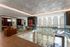 Elegant modern interior featuring a spacious lounge area with stylish furniture and a stunning glass railing overlooking a unique artistic chandelier.