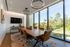 Elegant conference room with modern lighting, large windows offering scenic views, and a stylish wooden table with leather chairs.