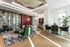 Elegant modern living space with chic green velvet chairs, artistic ceiling, glass cabinetry, and a cozy dining area bathed in natural light.