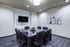 Elegant modern conference room with a glass table and plush chairs, featuring abstract art and a wall-mounted TV.