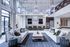 Luxurious open-concept living room with high ceilings, elegant chandeliers, modern kitchen, and stylish decor.