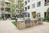 Chic apartment courtyard featuring modern outdoor grills, lush greenery, and stylish seating under elegant umbrellas, perfect for al fresco dining and relaxation.