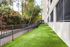 Inviting outdoor area with lush green artificial turf and a secure metal fence, perfect for relaxation and play, adjacent to a modern apartment building.