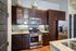 Modern kitchen with elegant dark wood cabinets, stainless steel appliances, and a granite countertop, showcasing a stylish and functional cooking space.