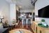 Modern open-concept living space with elegant dining area and sleek kitchen featuring dark cabinetry and stainless steel appliances.