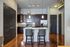 Modern kitchen with elegant island seating, granite countertops, and stainless steel appliances beneath stylish pendant lighting.