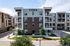 Apartment building entrance in Cedar Park with brick and stucco facade, balconies, and landscaped drive