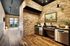 Resident clubroom kitchen with exposed brick, stainless dishwasher, beverage fridge, and wood plank flooring