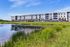 Community pond with native grasses and four story apartment buildings in Cedar Park