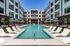 Courtyard pool with white lounge chairs, umbrellas, and four story apartment balconies in Cedar Park