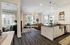 Kitchen island with black countertop, apron sink, and pendant lights open to a living room with wood plank floors