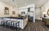 Kitchen island with four barstools, black countertop, stainless appliances, and wood plank flooring