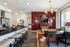 Kitchen island with barstools open to a dining area with chandelier, accent wall, and wood plank flooring
