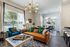 Living room with wood plank flooring, tall windows, breakfast bar seating, and doors to a private patio