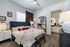 Bedroom with ceiling fan, wood plank flooring, and doorway to the bathroom vanity with lighted mirror