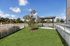 Fenced dog park with grass lawn, shade pavilion, and bench beside the apartment building