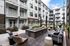 Courtyard fire pit with lounge chairs, sofa seating, string lights, and apartment balconies above