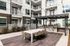 Grilling pavilion with gas grills, shaded dining table, and apartment balconies above