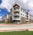 Apartment building corner in Cedar Park with stacked balconies, brick facade, and landscaped lawn