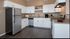 Kitchen with white cabinets, stainless refrigerator and range hood