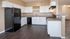 Kitchen with black appliances, white cabinets and wood plank flooring