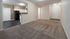 Living room with carpet, entry door and view into the kitchen