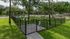 Dog park with black metal fence, gate and shade trees
