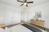 Elegant bedroom featuring a modern ceiling fan, minimalist decor, and a stylish wooden dresser with decorative vases.