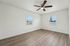 Bright, spacious bedroom with large windows, sleek wood flooring, and a modern ceiling fan.