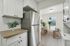 Modern kitchen with stainless steel fridge, white cabinets, and a cozy dining area with natural light.