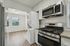 Modern kitchen with sleek stainless steel appliances, stacked washer and dryer, granite countertops, and large window for natural light.