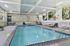Elegant indoor swimming pool area with bright natural lighting, lounge chairs, and poolside seating.