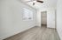 Bright and airy bedroom with stylish wood flooring, featuring a large window with blinds and a modern ceiling fan.
