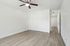 Bright, modern room with sleek wooden floors, fresh white walls, and a stylish ceiling fan. The space features ample storage with sliding closet doors, offering a clean and airy ambiance.
