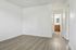 Bright and airy blank room with sleek wood flooring and a glimpse into a modern bathroom with elegant cabinetry.