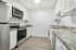 Modern kitchen featuring sleek white cabinetry, stainless steel appliances, and elegant granite countertops.