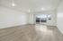 Bright and spacious living room with sleek hardwood floors and large glass doors leading to a sunny balcony.