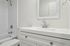 Elegant modern bathroom with a sleek white vanity, polished chrome fixtures, and a pristine tiled shower.