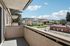 Charming apartment balcony with scenic urban views, bright blue skies, and lush greenery.