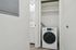 Modern apartment laundry area featuring a sleek washing machine and built-in shelving.