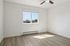 Bright and airy bedroom with a large window, elegant ceiling fan, and stylish wood flooring.