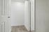 Bright, minimalist hallway with modern wood flooring and crisp white doors, offering a sleek and inviting entrance.