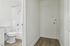 Modern bathroom with sleek white fixtures, a pristine bathtub, and stylish wooden flooring.